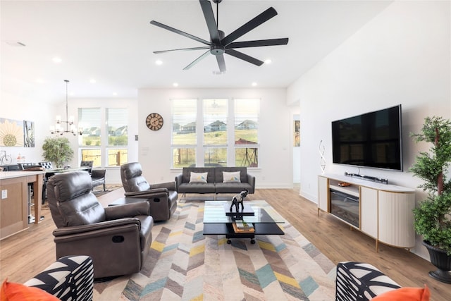 living room with ceiling fan with notable chandelier and light hardwood / wood-style floors