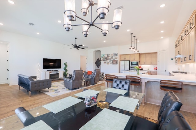 dining room with a fireplace, light hardwood / wood-style flooring, and ceiling fan with notable chandelier