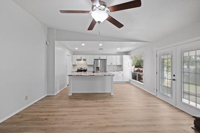 kitchen with lofted ceiling, french doors, light hardwood / wood-style flooring, appliances with stainless steel finishes, and white cabinetry