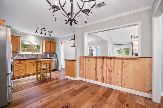 kitchen with sink, stainless steel appliances, tasteful backsplash, light hardwood / wood-style flooring, and a notable chandelier