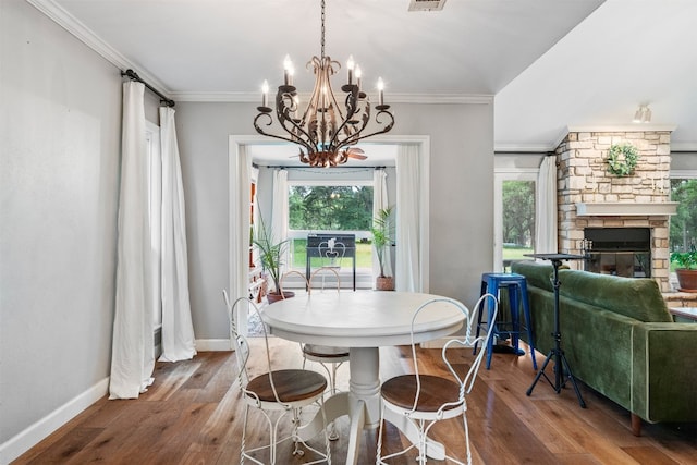 dining room with hardwood / wood-style flooring, a stone fireplace, and ornamental molding