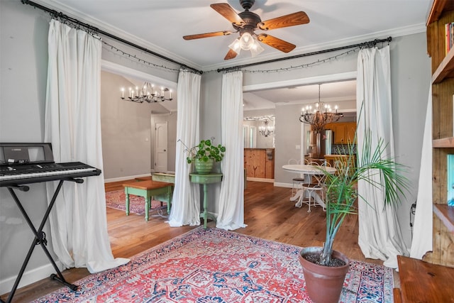 interior space featuring wood-type flooring, ceiling fan with notable chandelier, and crown molding