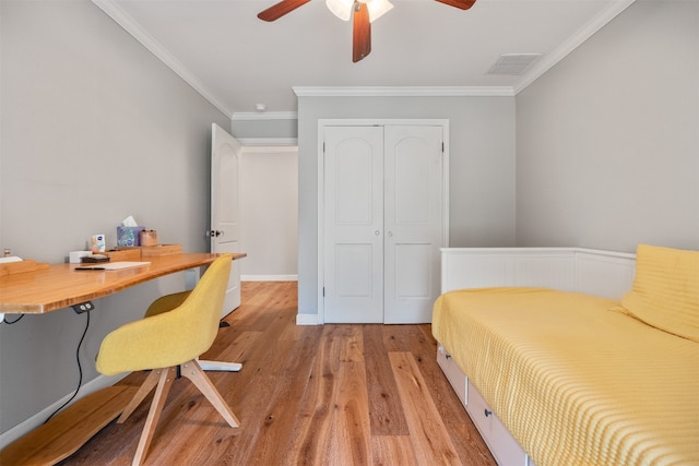 bedroom featuring light wood-type flooring, a closet, ceiling fan, and ornamental molding