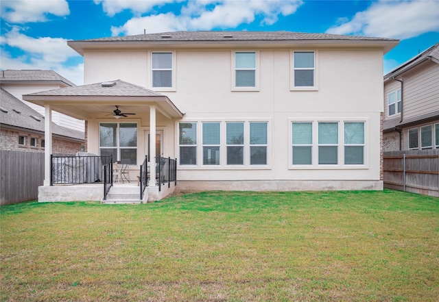 rear view of property featuring ceiling fan and a yard