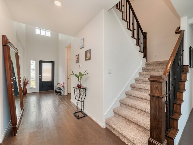 entryway featuring a towering ceiling and dark wood-type flooring