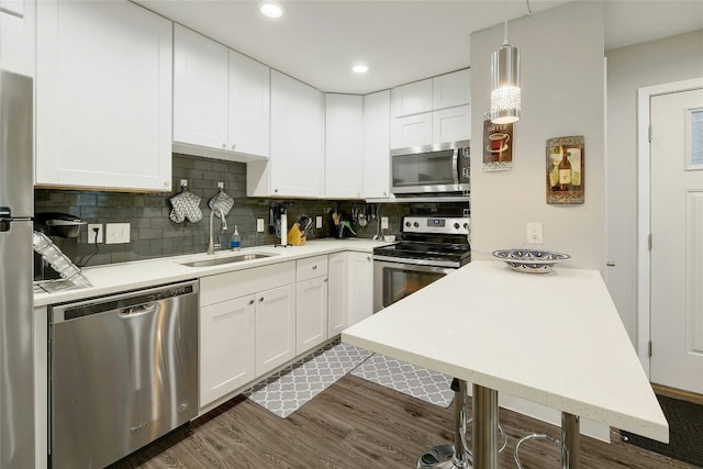 kitchen featuring tasteful backsplash, stainless steel appliances, sink, decorative light fixtures, and white cabinetry