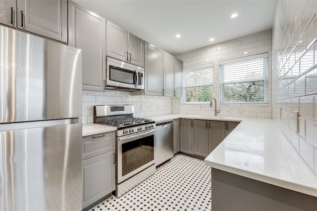 kitchen featuring gray cabinets, decorative backsplash, sink, and stainless steel appliances