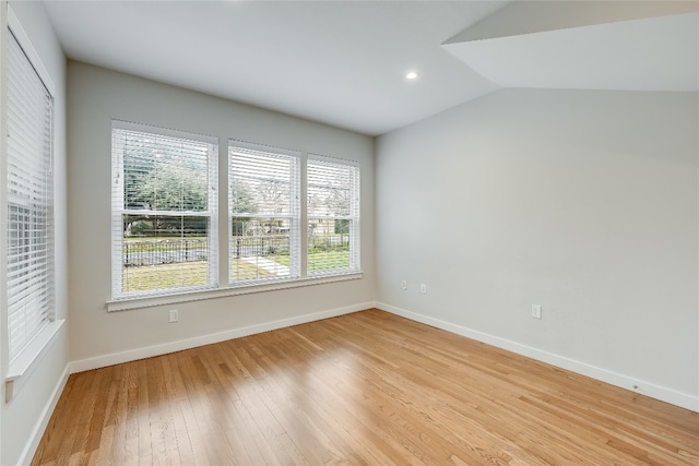 empty room with plenty of natural light, lofted ceiling, and light hardwood / wood-style flooring