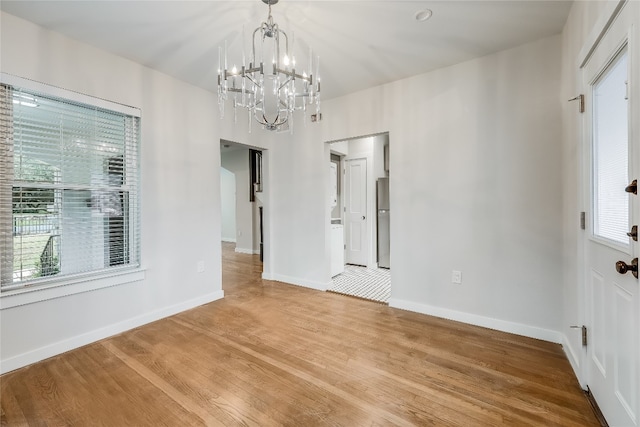 unfurnished dining area featuring hardwood / wood-style floors and an inviting chandelier