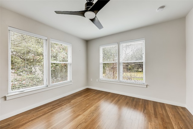 spare room with plenty of natural light, ceiling fan, and wood-type flooring