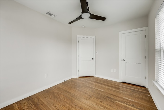 unfurnished bedroom featuring hardwood / wood-style flooring, ceiling fan, and multiple windows