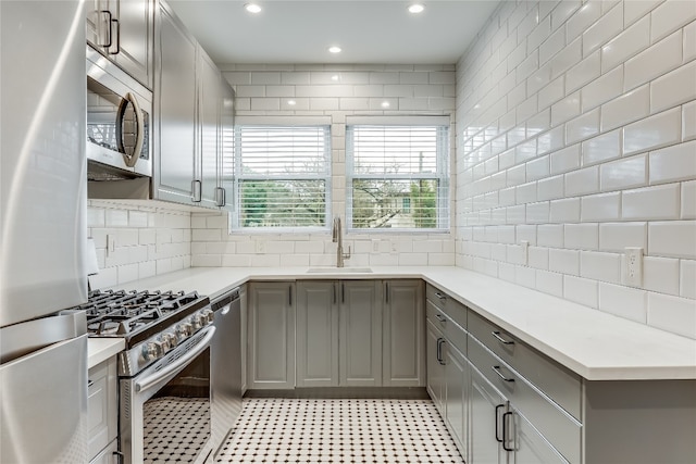 kitchen with decorative backsplash, stainless steel appliances, gray cabinets, and sink