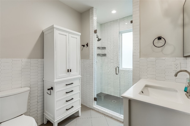 bathroom featuring vanity, tile patterned floors, toilet, tile walls, and a shower with shower door