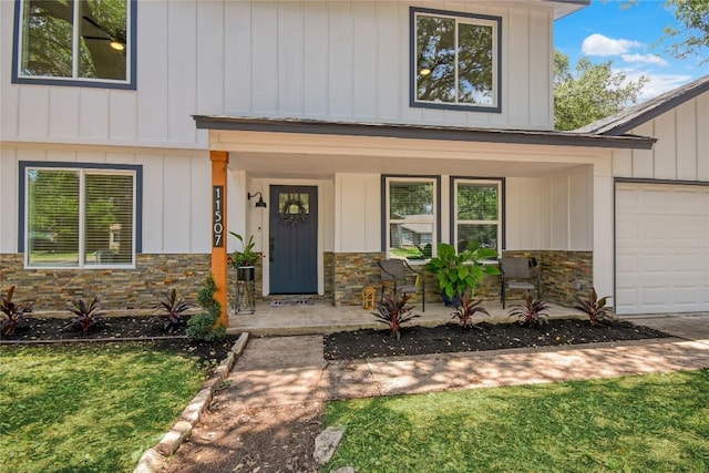 entrance to property featuring a garage, a yard, and covered porch