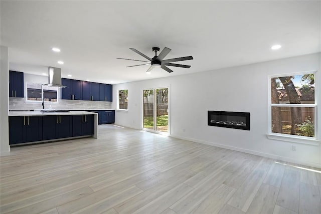 unfurnished living room with plenty of natural light, ceiling fan, and light wood-type flooring