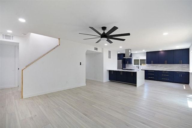 unfurnished living room with sink, ceiling fan, and light hardwood / wood-style floors