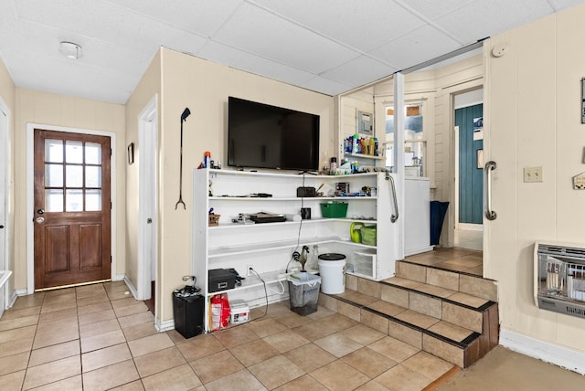 interior space featuring heating unit, a drop ceiling, and light tile patterned floors