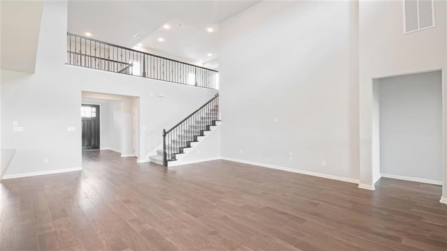 unfurnished living room featuring a high ceiling and dark wood-type flooring