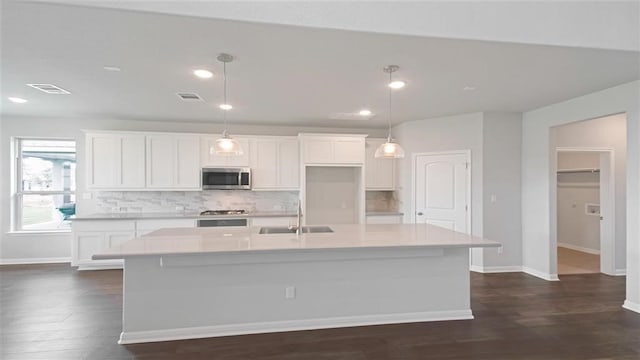 kitchen with hanging light fixtures, a kitchen island with sink, sink, and stainless steel appliances