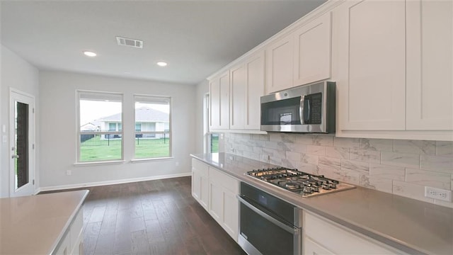 kitchen featuring tasteful backsplash, dark hardwood / wood-style flooring, white cabinets, and appliances with stainless steel finishes