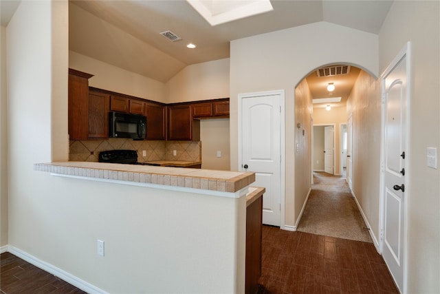 kitchen featuring kitchen peninsula, backsplash, vaulted ceiling, black appliances, and tile countertops