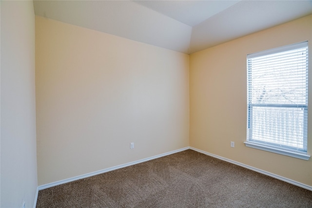 carpeted empty room featuring vaulted ceiling