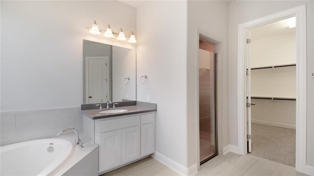 bathroom with vanity and tiled tub