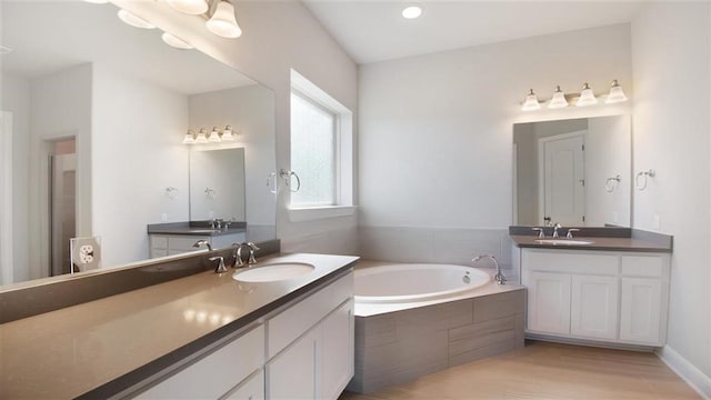 bathroom featuring vanity, wood-type flooring, and tiled tub