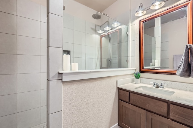 bathroom with a tile shower and vanity