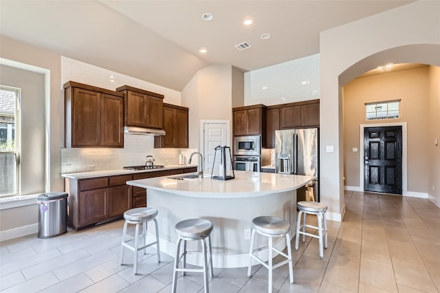 kitchen with a breakfast bar, sink, an island with sink, and stainless steel appliances