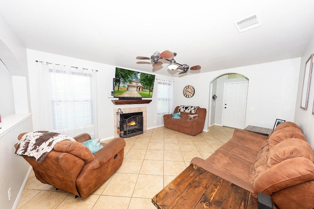 tiled living room featuring ceiling fan and a tile fireplace