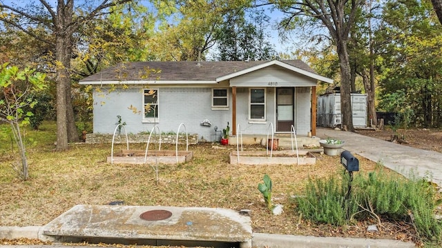 view of front of property featuring brick siding, a storage unit, and a front yard