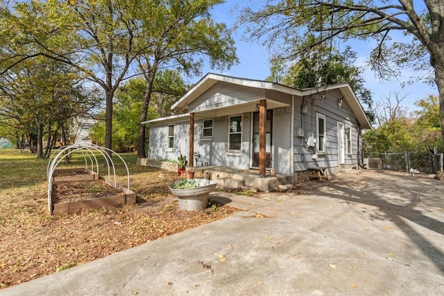 bungalow-style house featuring concrete driveway, a garden, and fence