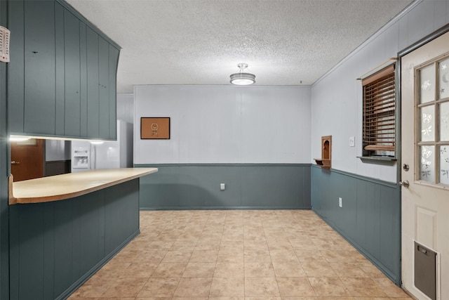 kitchen featuring kitchen peninsula, white fridge with ice dispenser, and a textured ceiling