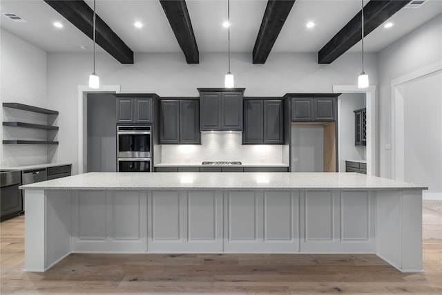 kitchen featuring beam ceiling, light stone countertops, stainless steel appliances, light hardwood / wood-style flooring, and a spacious island