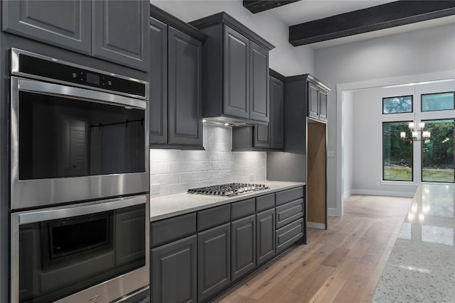 kitchen featuring tasteful backsplash, light stone counters, stainless steel appliances, beamed ceiling, and light hardwood / wood-style floors