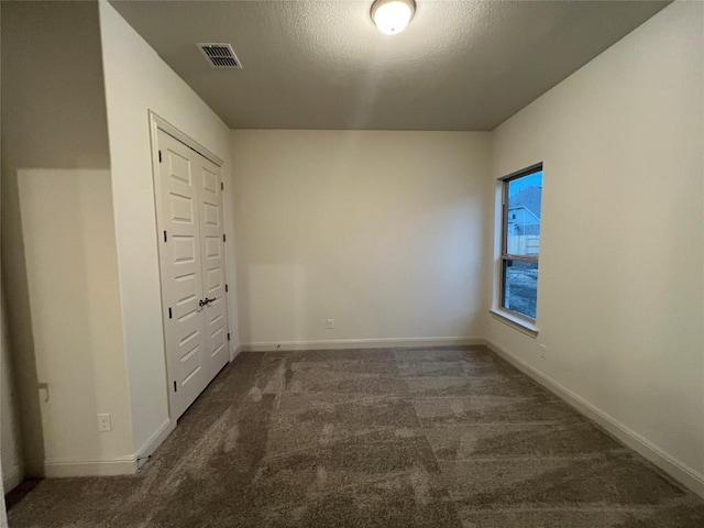 carpeted empty room with a textured ceiling