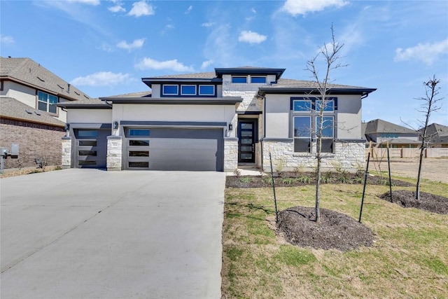 prairie-style house with stucco siding, stone siding, a garage, and concrete driveway