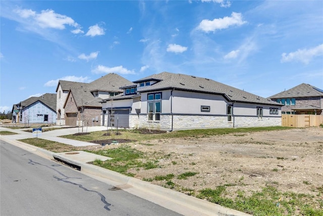 view of side of property with fence, a residential view, stucco siding, a garage, and stone siding