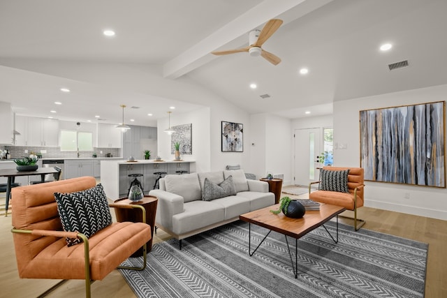 living room featuring lofted ceiling with beams, light hardwood / wood-style flooring, and ceiling fan