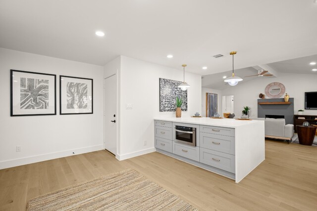 kitchen featuring kitchen peninsula, light hardwood / wood-style floors, lofted ceiling, and hanging light fixtures