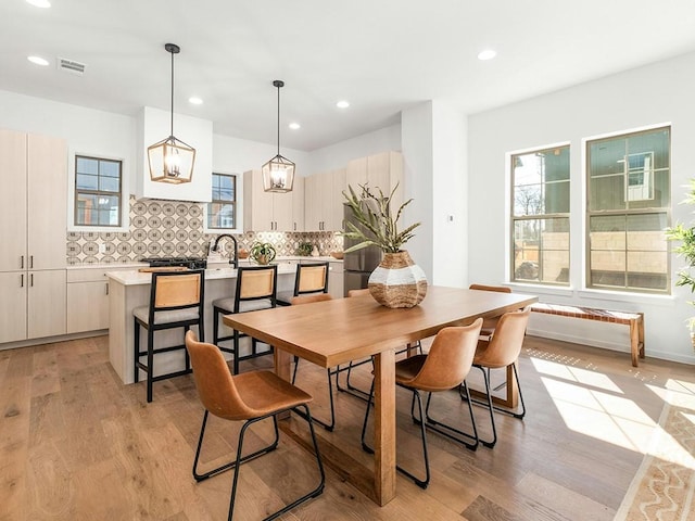 dining space featuring sink, light hardwood / wood-style flooring, and a healthy amount of sunlight