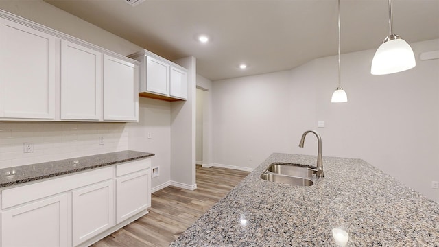 kitchen with white cabinets, decorative light fixtures, sink, and dark stone counters