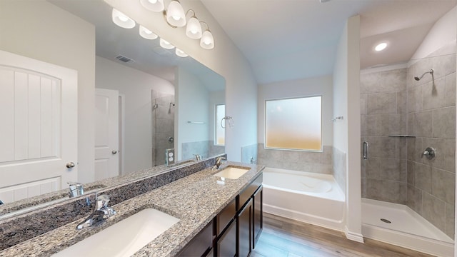 bathroom with plus walk in shower, hardwood / wood-style floors, vanity, and vaulted ceiling