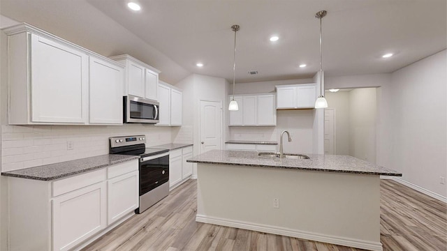 kitchen featuring a sink, an island with sink, light wood-type flooring, stainless steel appliances, and backsplash