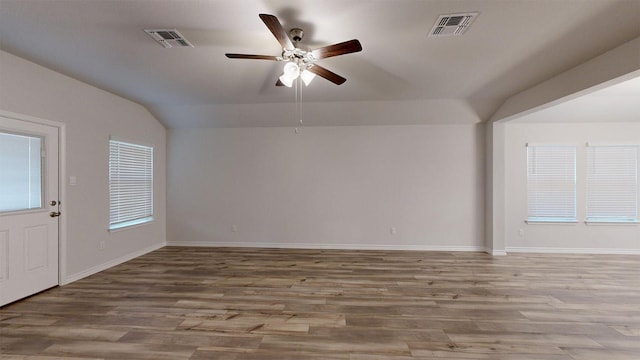empty room with baseboards, visible vents, lofted ceiling, a ceiling fan, and wood finished floors