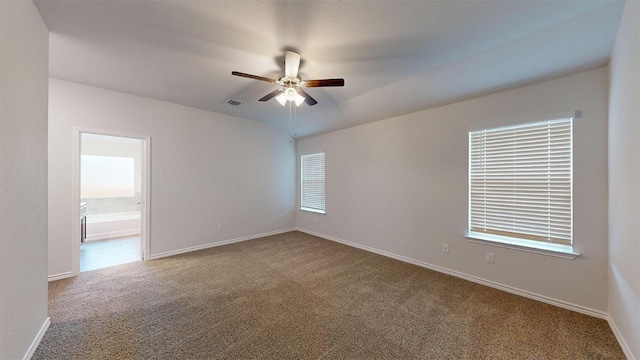 carpeted spare room with visible vents, baseboards, and ceiling fan