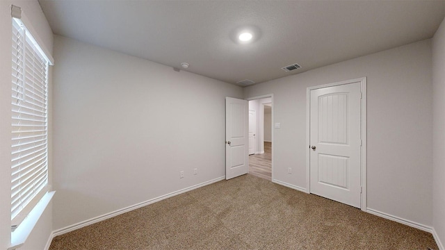 unfurnished bedroom featuring baseboards, carpet flooring, multiple windows, and visible vents
