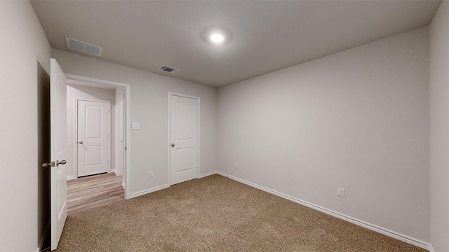 carpeted spare room featuring visible vents and baseboards