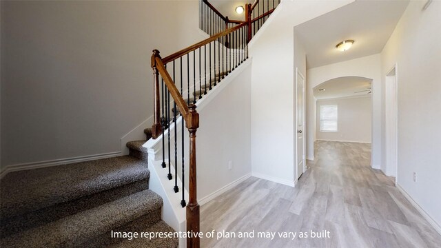 stairs featuring hardwood / wood-style flooring and ceiling fan